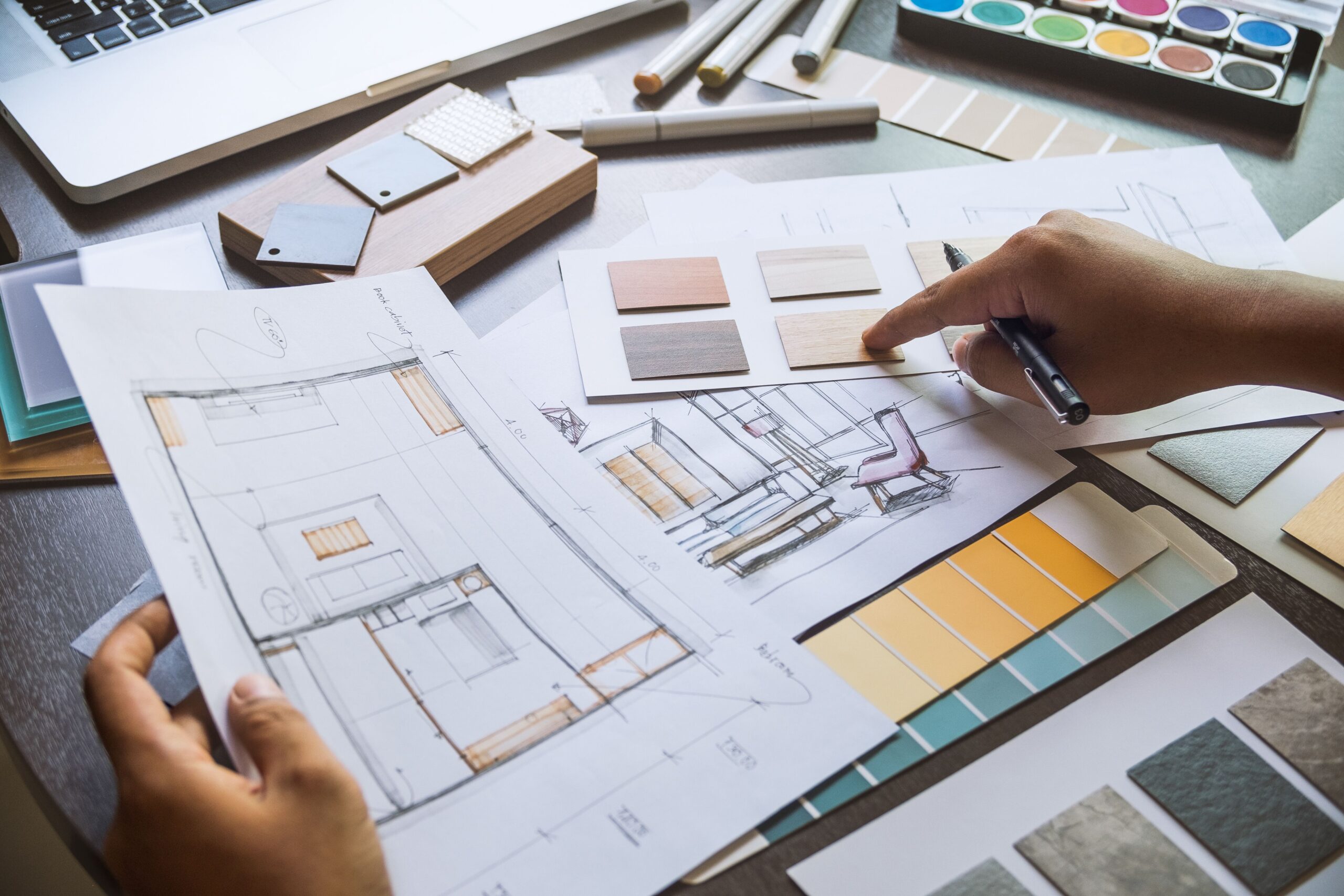 A designer selects materials and colors from swatches and sketches while planning an interior design project, showcasing creativity and design process.